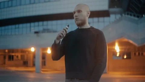 Modern man vaping outside in the warm summer evening Stockbeeldmateriaal 85612327