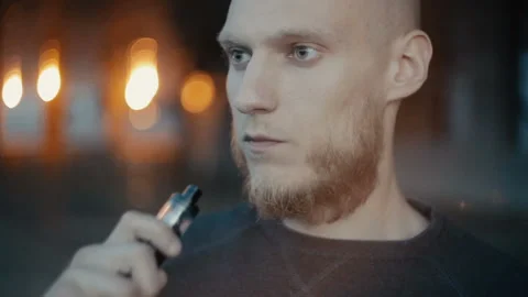 Modern man vaping outside in the warm summer evening Stockbeeldmateriaal 85612441