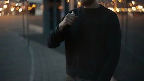 Modern man vaping outside in the warm summer evening Stockbeeldmateriaal 85612572
