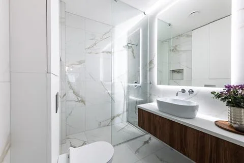 Modern Marble Bathroom Interior With Floating Vanity, Backlit Mirror and Gl.. Stock Photos