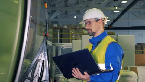 Modern mechanism is being managed through the laptop by the worker Stock Footage 105646604