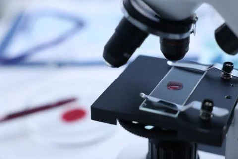 Modern medical microscope with sample of red liquid in laboratory, closeup... Stock Photos