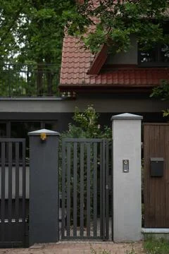 Modern metal intercom gate stands closed near a private suburban house exteri Stock Photos