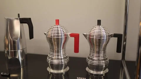 Modern metallic coffee makers with ribbed design and colored handles displayed o Stock Footage 318869616