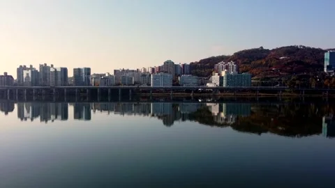 Modern metropolitan skyline rises beyond broad river and bridge in wide Stock Footage 344800541