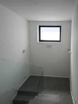 Modern microcement interior staircase in common area with glass railing Stock Photos