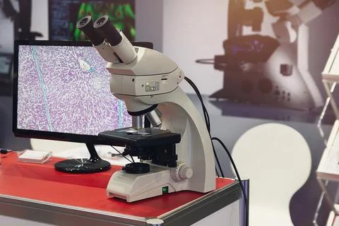 Modern microscope and slide section of human tissue with computer monitor Fotos de archivo