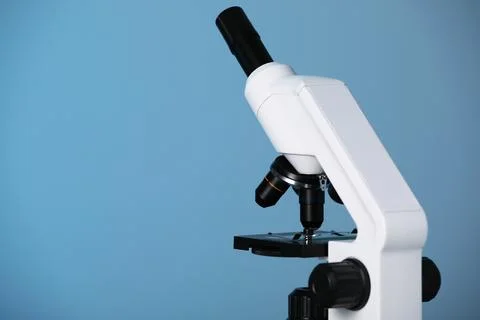 Modern microscope on blue background. Space for text Stock Photos