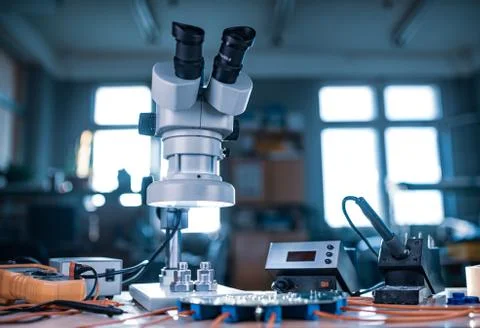 Modern microscope, connectors component and large green microcircuit in works Stock Photos