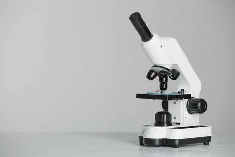 Modern microscope on grey background. Space for text Stock Photos