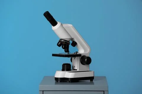 Modern microscope on table against blue background. Medical equipment Stock Photos