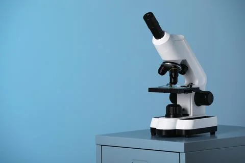 Modern microscope on table against blue background. Space for text Stock Photos