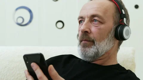 Modern middle-aged man listens to music in wireless headphones Stock Footage 197432078