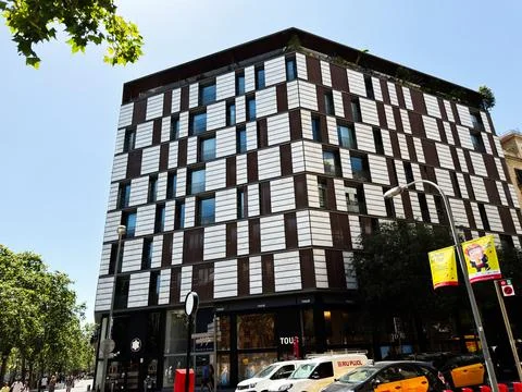 Modern mixed-use building with patterned faade and street-level shops on a .. Stock Photos