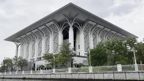 Modern mosque stands beside calm water under cloudy sky Stock Footage 340034404