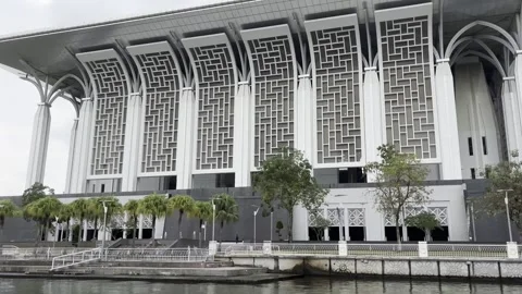 Modern mosque stands beside calm water under cloudy sky Stock Footage 340034406