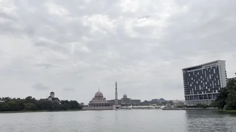 Modern mosque stands beside calm water under cloudy sky Stock Footage 340034420