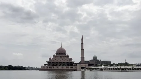 Modern mosque stands beside calm water under cloudy sky Stock Footage 340034430
