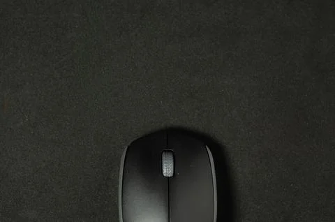 Modern mouse rests on dark surface. Stock Photos