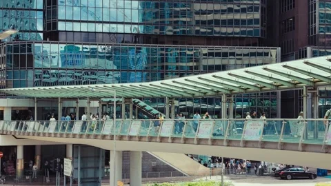 A modern multi-level pedestrian bridge spanning a bustling cityscape in Hong Stock Footage 338311446