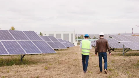 In a modern new large solar panels farm two ecological engineers walking through Stock Footage 164546222