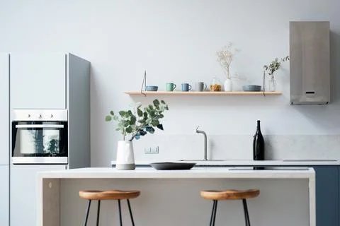 Modern new light interior of kitchen with white furniture and dining table. Stock Photos