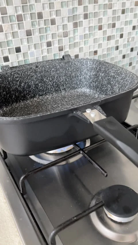 Modern, new rectangular frying pan with handle and protective coating on gas Stock Footage 318464481