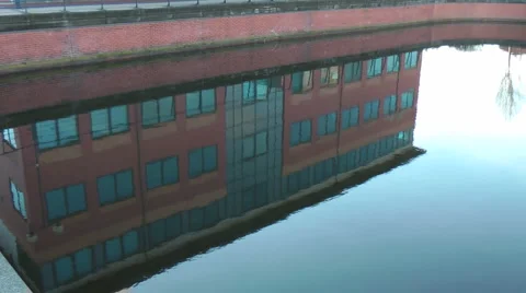 Modern office block reflected in water, pan up to building. Stock Footage 1059294