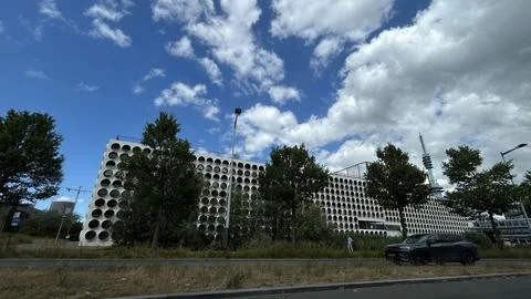 Modern office building with circular window pattern beside road, framed by Stock Photos
