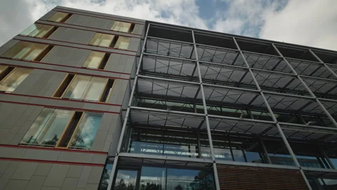 Modern office building facade with stone cladding, red accent strips and glass Stock Footage 346240654