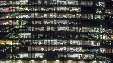 Modern office building with large windows at night, light shines in the windo Stock Footage