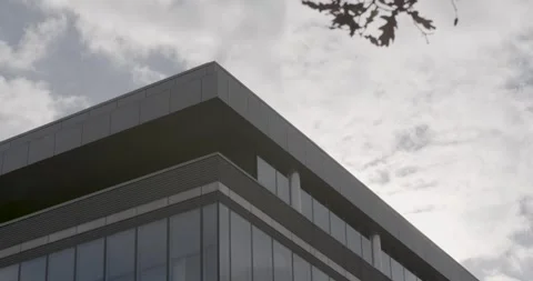 Modern office building with reflective windows under a cloudy sky, Vídeos de archivo 275012517