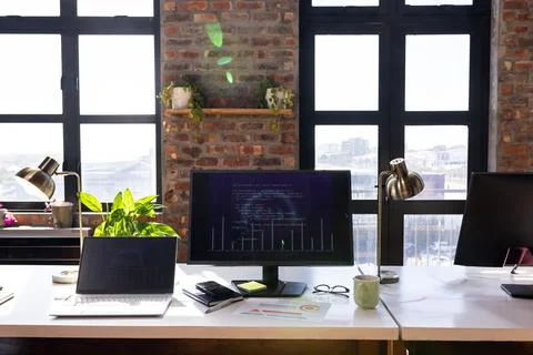 Modern office desk with computer screen displaying code and business charts Stock Photos