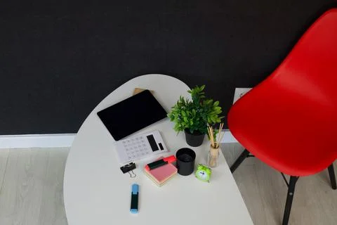 Modern office desk setup with tablet, calculator, and red chair Stock Photos