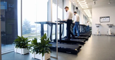 Modern office gym, two men are walking on the treadmills and working, 4k Stock Footage 129322933