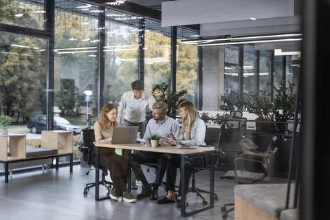 A modern office interior, featuring a blurred view of workers at desks, throu Stock-Fotos
