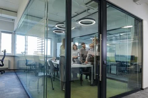 A modern office interior, featuring a blurred view of workers at desks, throu Foto stock