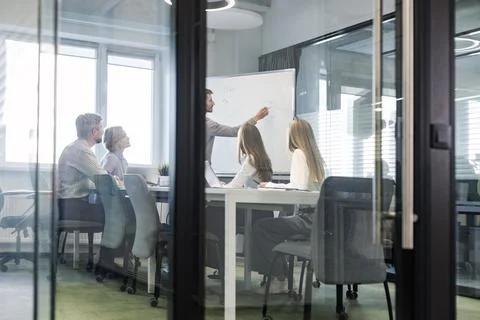 A modern office interior, featuring a blurred view of workers at desks, throu Stock Photos