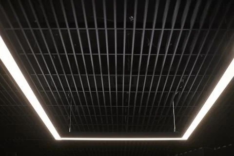 Modern office lighting. Thin lamps in office dark ceiling. LED white cold lig Stock Photos
