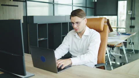 In a modern office, a man sits at his computer looking concerned as a female Stock Footage 326703737