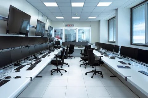 A modern office with rows of computer workstations and black office chairs Stock Photos