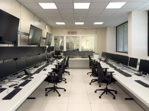A modern office space with rows of computers and large monitors Stockfoto's
