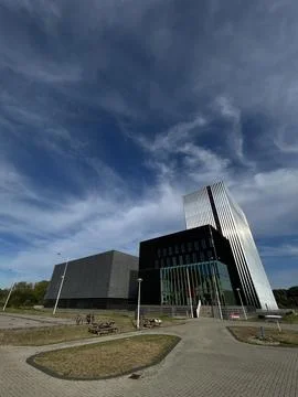 Modern office tower and low rise business building beneath dramatic blue sky Stock Photos