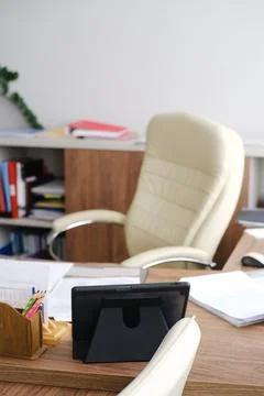 Modern office workspace featuring a stylish ergonomic chair, tablet on desk Stock Photos