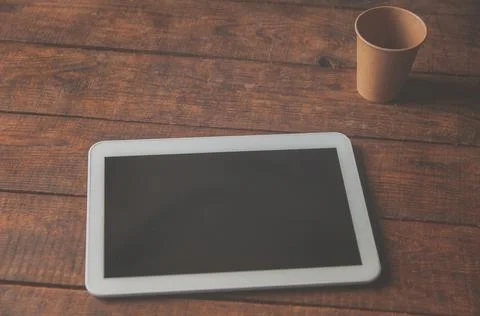 Modern office workspace with tablet pc on the table and a disposable cup of c Stock Photos