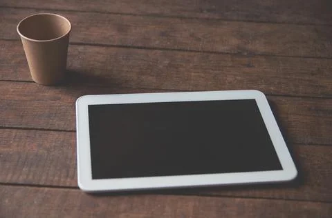 Modern office workspace with tablet pc on the table and a disposable cup of c Stock Photos