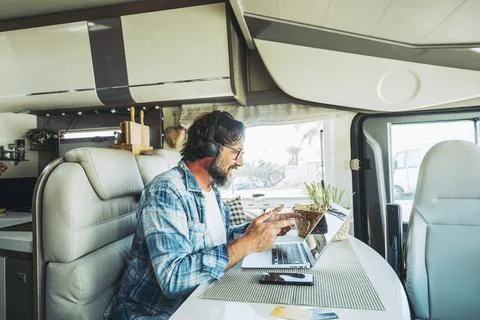 Modern online worker smart working digital nomad lifestyle in camper van. T.. Stock Photos