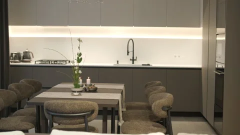Modern open-plan kitchen and dining area with grey cabinets and LED lighting. Stock Footage 329999223