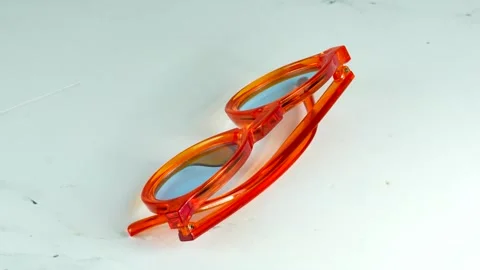 Modern orange transparent glasses rotating 360 degrees on a white background 스톡 동영상 334554038