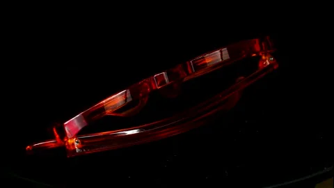 Modern orange transparent glasses rotating 360 degrees on a black background 스톡 동영상 334594012